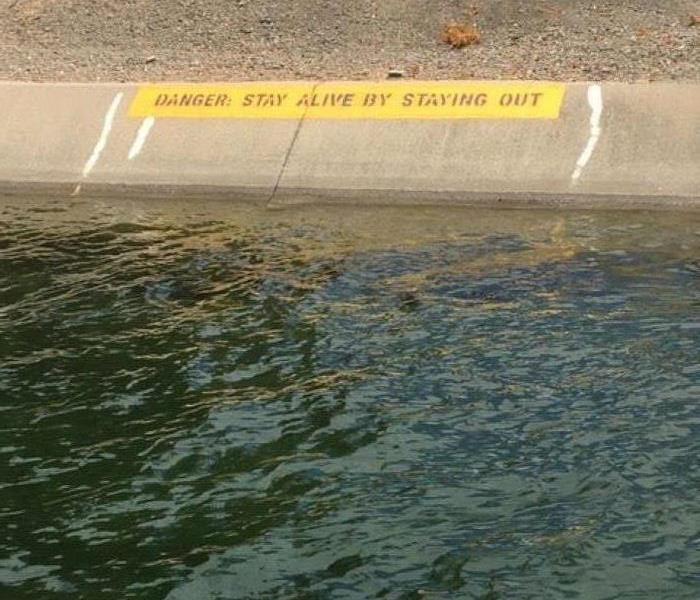 Picture shows water with sign saying "Danger: Stay Alive by Staying Out"