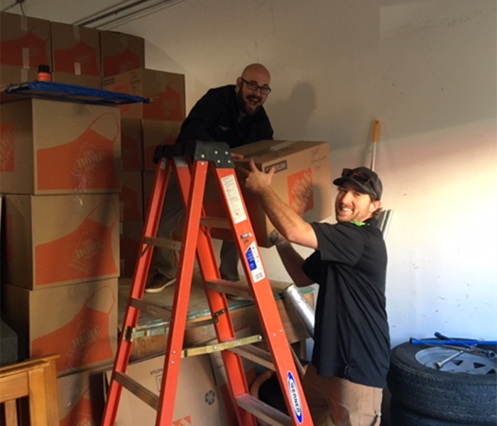 Picture shows two employees on ladder packing boxes