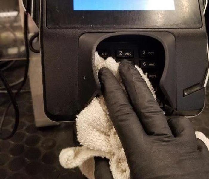 Picture shows hand cleaning a credit card machine
