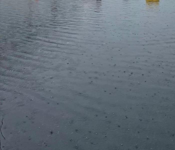 image shows parkig lot flooded with water and truck in background